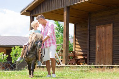 Baba yakınında küçük bir ata binerken oğlu inanılmaz hissediyor
