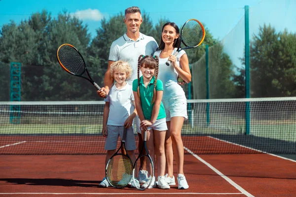 Padres e hijos sintiéndose felices y alegres después de jugar tenis —  Fotos de Stock