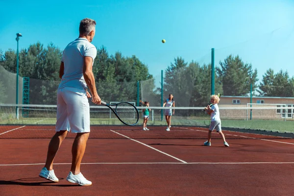 Щаслива сім'я любить спорт, граючи в теніс на вихідних — стокове фото