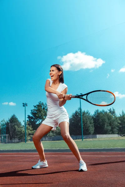 Mulher de cabelos escuros gritando ao bater a bola de tênis — Fotografia de Stock