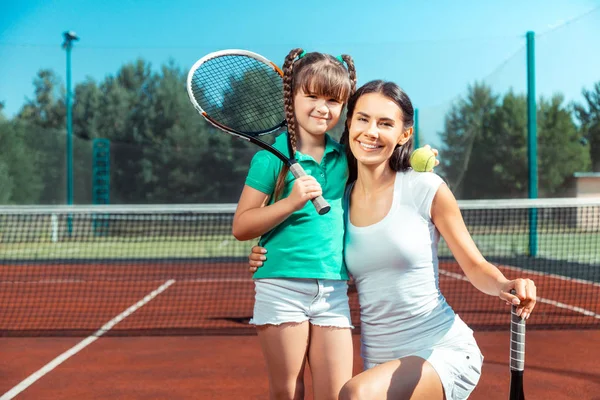 Mami e hija sosteniendo raquetas de tenis y sonriendo —  Fotos de Stock