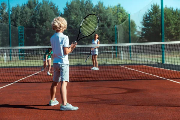 卷曲的儿子拿着网球拍，而打网球 — 图库照片