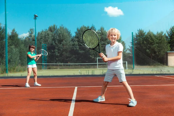 Lindo chico sintiéndose feliz jugando tenis con su mejor amigo —  Fotos de Stock