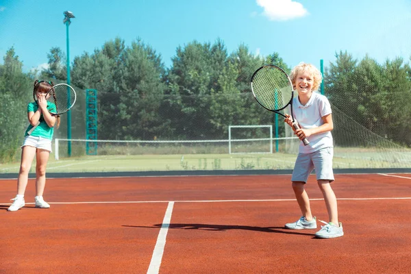 Alegre hermano sintiéndose feliz jugando tenis con hermana —  Fotos de Stock