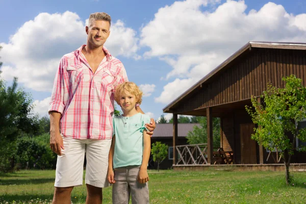 Stilig far klädd i vita shorts kramar hans söta son — Stockfoto