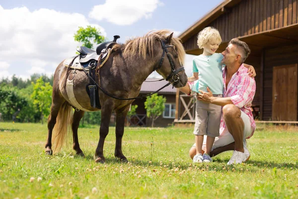 Vader knuffelen zoon terwijl komen dichter bij paard samen — Stockfoto