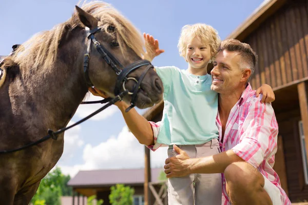 Fils souriant tout en touchant le cheval pour la première fois — Photo