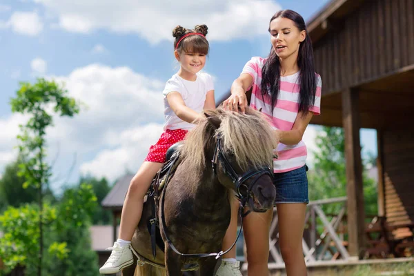 Sötét hajú lány élvezi lovaglás vele gondoskodó anya — Stock Fotó