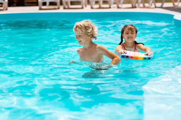 Hermano y hermana sintiéndose alegres y alegres nadando en la piscina — Foto de Stock