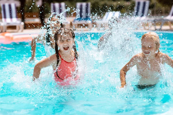 Les enfants rient en éclaboussant l'eau dans la piscine — Photo