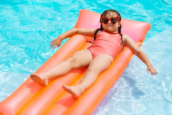 Legrační dívka na brýlích na vzduchové matraci v bazénu — Stock fotografie