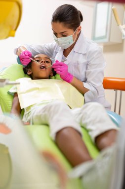 Diş hekimi koltuğunda yatan genç kadın hasta