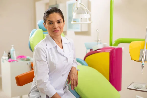 Pleased female doctor sitting in a dentist office — Stock Photo, Image