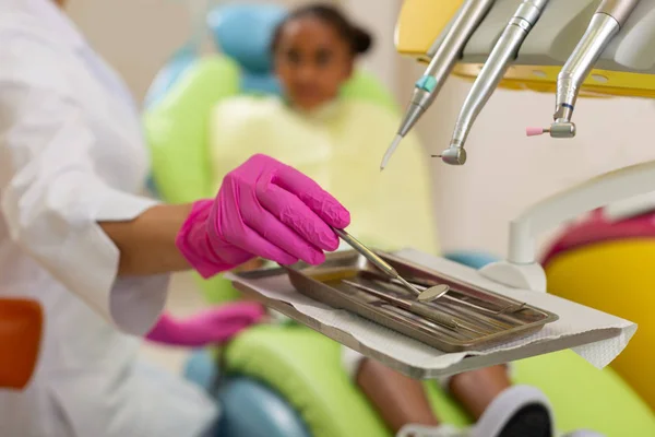 Female dentists hands in gloves holding a mirror