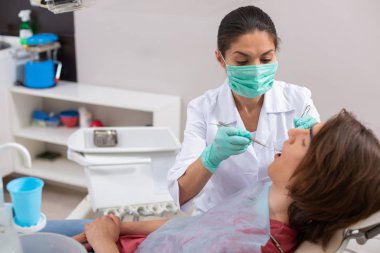 Diş sandalyesinde yatan koyu saçlı erkek hasta