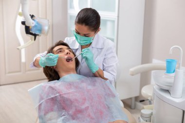 Yeşil maskeli konsantre ciddi kadın doktor