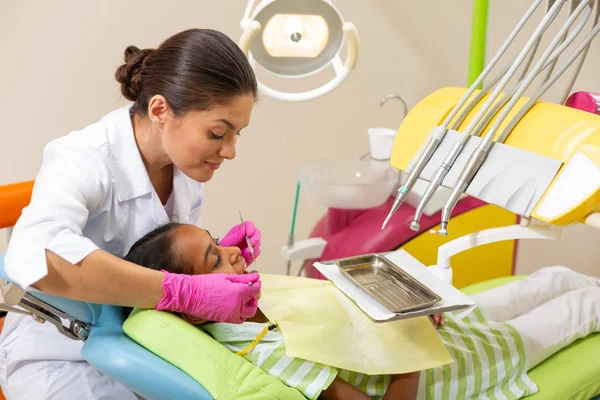 Middle-aged woman dentist examining her young female patient