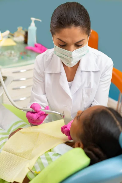 Woman dentist leaning over a young female patient