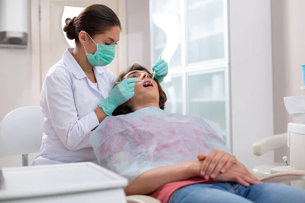 女牙医用牙科仪器探查她的男性病人牙齿 — 图库照片
