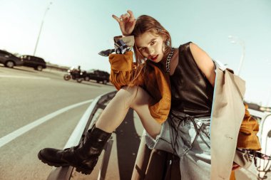 Languid koyu saçlı genç model yeni bir koleksiyondan giysi gösteren