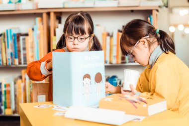 Parlak gömlekli koyu saçlı kızlar öğrenme materyalleri ile meşgul