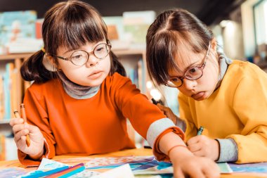 Curious dark-haired girl in eyeglasses taking new color of pencil clipart