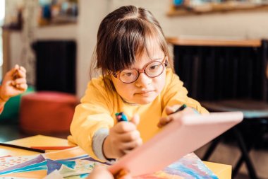 Tablet fırsatları yaşayan boya kalemleri ile kararlı koyu saçlı çocuk