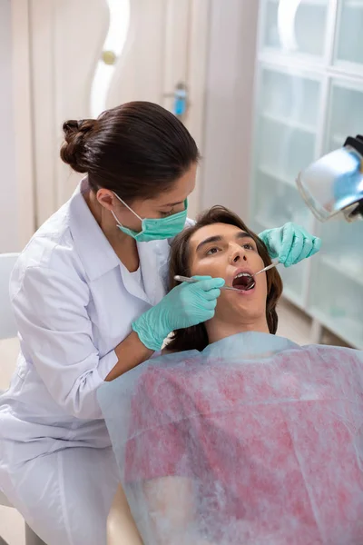 Молодий коричневоокий чоловік лежить у стоматологічному кріслі — стокове фото