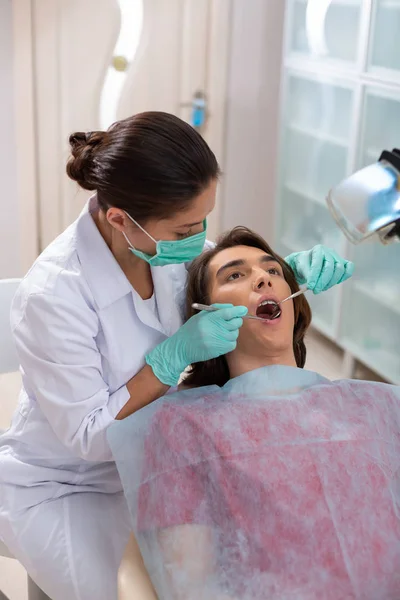 Giovane uomo dagli occhi marroni sdraiato su una sedia dentale — Foto Stock