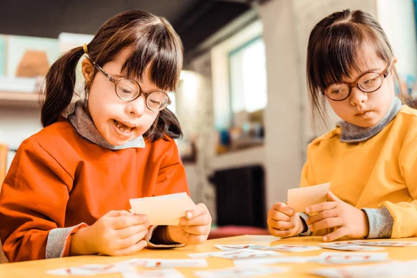 Chica sonriente en gafas de vista sentada con su hermana seria — Foto de Stock