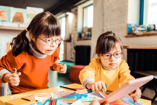 Expresivas niñas en gafas siendo sorprendidas con la tableta —  Fotos de Stock