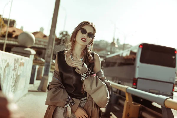 Appealing young lady in a dark sunglasses posing for photographer — Stock Photo, Image