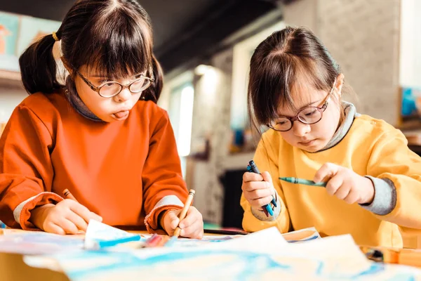 Niños poco concentrados con síndrome de Down trabajando en una nueva imagen —  Fotos de Stock