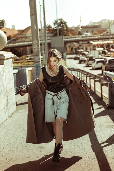 Dunkelhaarige schöne Dame zieht Oversize-Mantel aus — Stockfoto