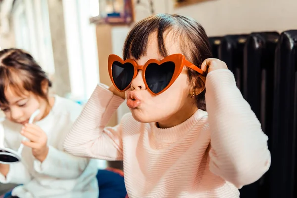 Espressivo giovane signora cercando su occhiali da sole a forma di cuore — Foto Stock