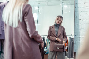 Pencere yakın sarışın Alışverişkoliğin ayakta el çantası seçimi