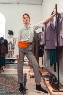 Moda butik ayakta turuncu bel çantası giyen Stilist
