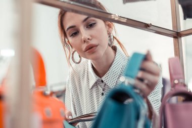 El çantaları bakarak benekli bluz giyen kırmızı saçlı tasarımcı