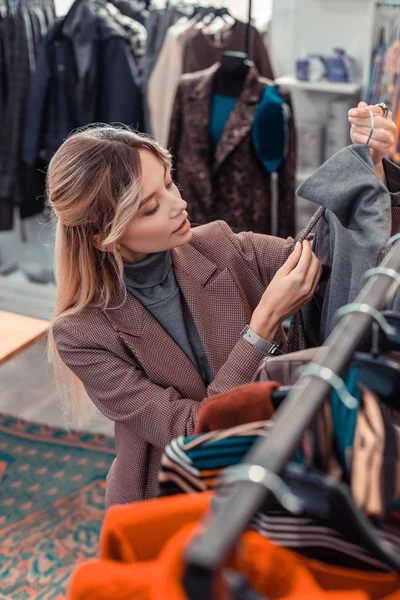 Mujer mirando la tela mientras elige ropa nueva — Foto de Stock