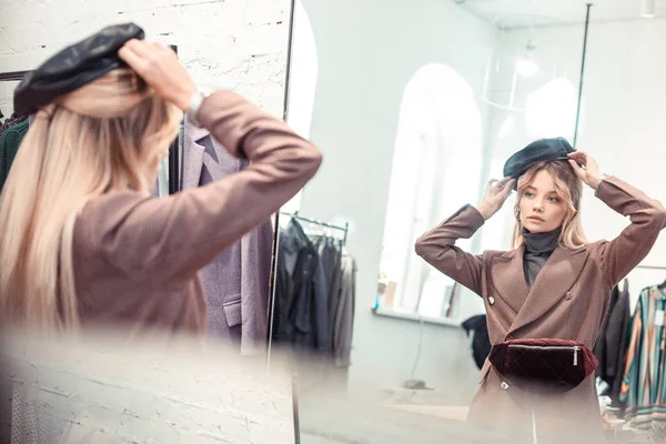 Rubia mujer de moda tratando de sombrero agradable durante las compras — Foto de Stock