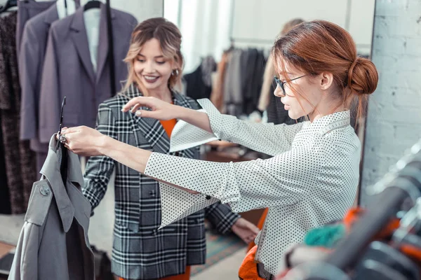 Shopping Assistant in glazen tonen klant mooie jas — Stockfoto