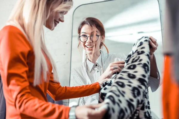 Blond kobieta uśmiechnięta patrząc na płaszcz z ładnym wzorem — Zdjęcie stockowe