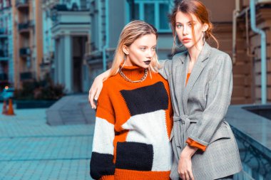 Moda kataloğu için dışarıda poz veren kızıl saçlı ve sarışın modeller