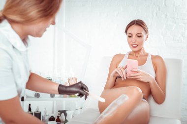 Beyaz iç çamaşırı yla yatan hoş genç kadın, usta bacaklarını kaplarken