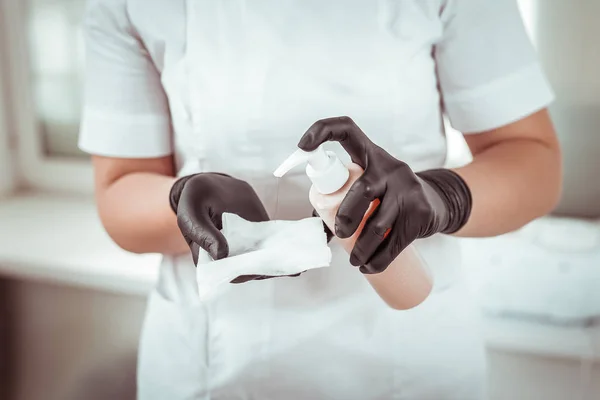 Professionelle Salonarbeiterin in Gummihandschuhen, die Antiseptikum versprüht — Stockfoto