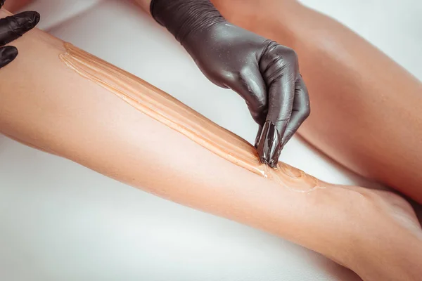 Accurate skilled woman using sugaring technique for her client — Stock Photo, Image