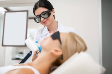 Hasta ile çalışma sırasında gülümseyen güzellik doktor.