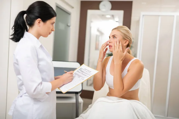 Mujer contándole a un médico de belleza sobre los procedimientos necesarios . —  Fotos de Stock