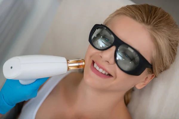 Sorridente donna ottenere il suo trattamento viso laser . — Foto Stock