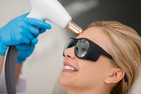 Mujer sonriendo durante su tratamiento de la piel de la cara láser . — Foto de Stock